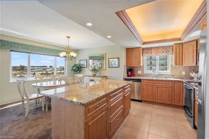 Kitchen featuring light stone countertops, decorative backsplash, stainless steel appliances, recessed lighting, and a center island