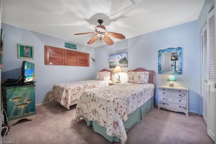 Bedroom with a textured ceiling, a closet, carpet flooring, and ceiling fan