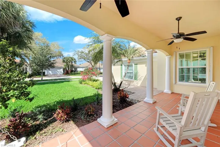Covered porch featuring ceiling fan and a yard