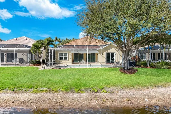Rear view of property featuring a patio area, an outdoor pool, a water view, a yard, and a lanai
