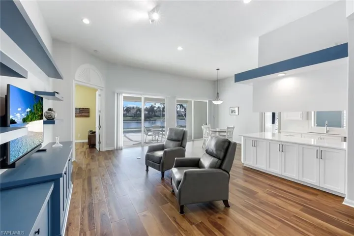 Living room featuring dark wood-type flooring, recessed lighting, and a water view