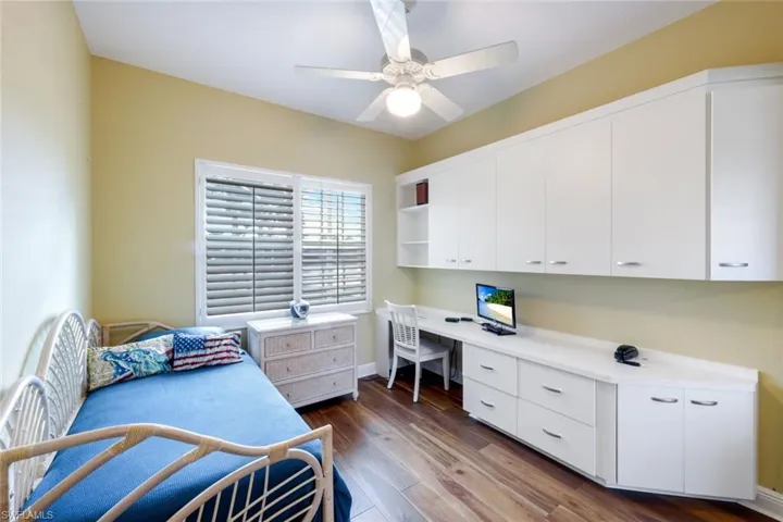 Bedroom featuring dark wood-style flooring, ceiling fan, and built in study area