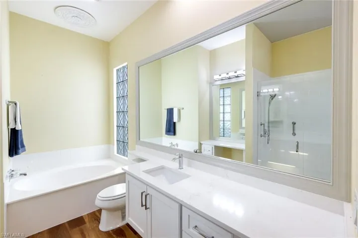 Full bath featuring vanity, a shower stall, dark wood-style floors, and a bath