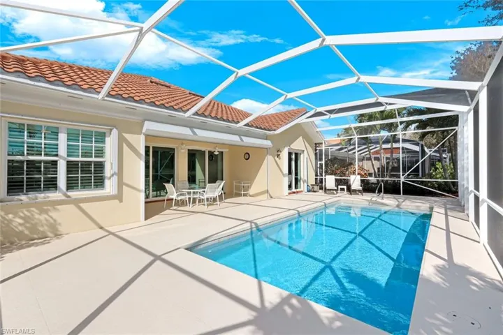 Outdoor pool with a sunroom, a patio area, glass enclosure, and outdoor dining area