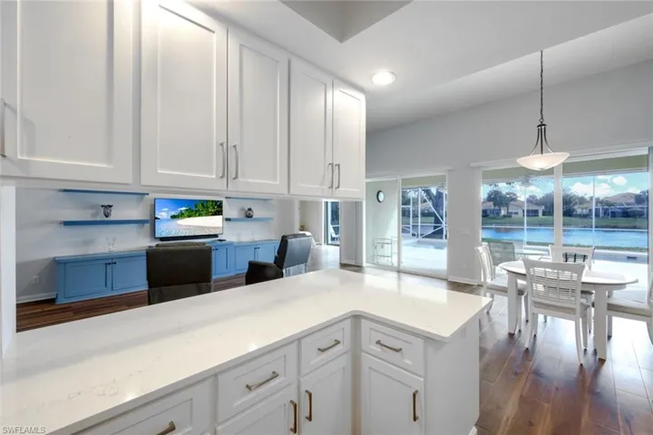 Kitchen featuring white cabinets, dark wood finished floors, decorative light fixtures, and light stone countertops