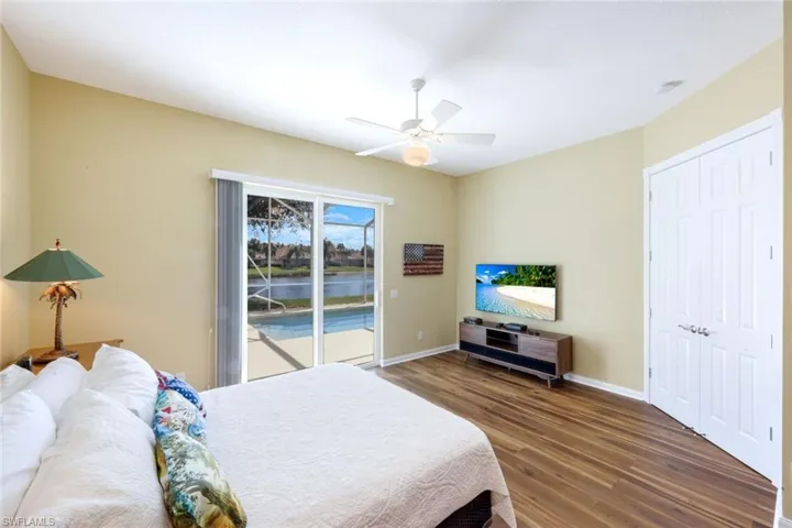 Bedroom featuring access to outside, dark wood-style flooring, a ceiling fan, and a closet
