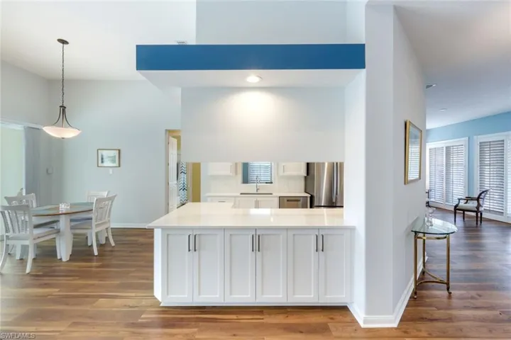 Kitchen with white cabinetry, dark wood-style flooring, stainless steel appliances, and a peninsula
