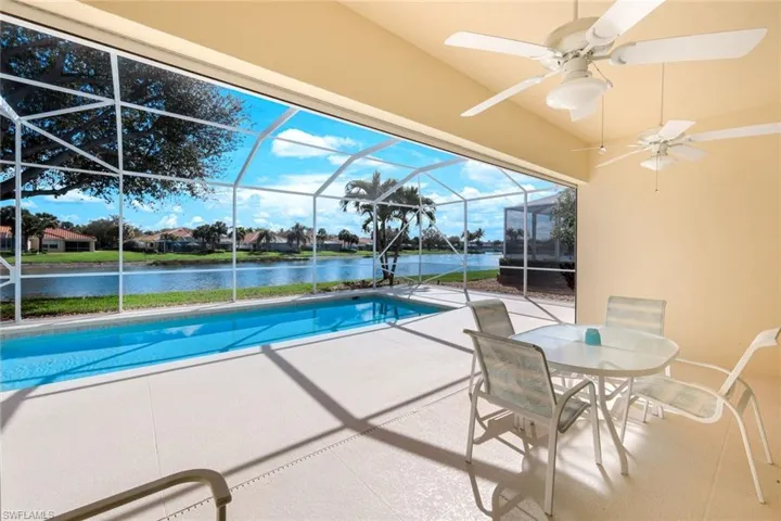 Swimming pool featuring a patio area, a sunroom, a lanai, a water view, and outdoor dining area