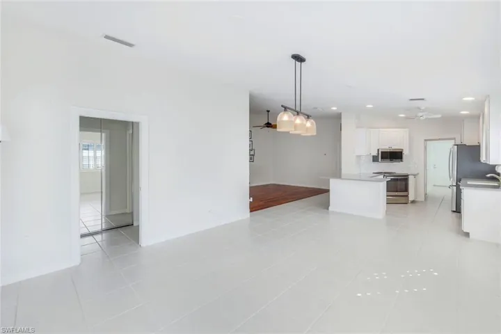 Kitchen featuring ceiling fan, hanging light fixtures, white cabinetry, open floor plan, and recessed lighting
