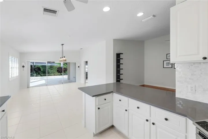 Kitchen with a peninsula, white cabinetry, recessed lighting, open floor plan, and light tile patterned floors