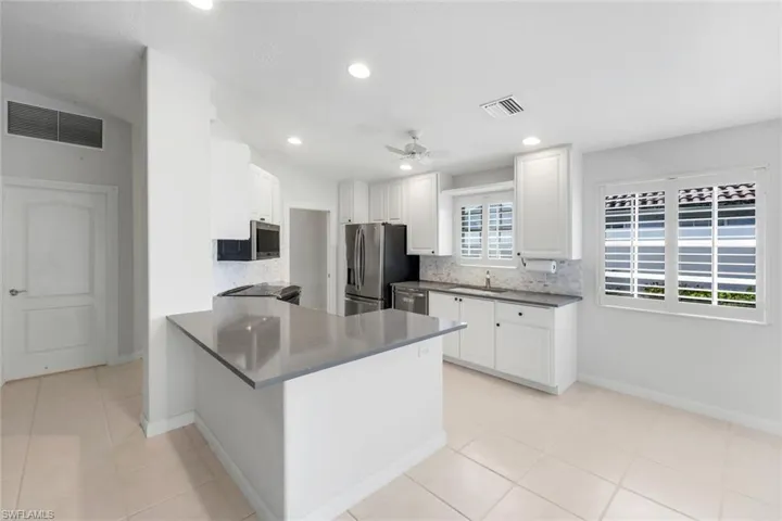 Kitchen with tasteful backsplash, a peninsula, light tile patterned flooring, stainless steel appliances, and recessed lighting