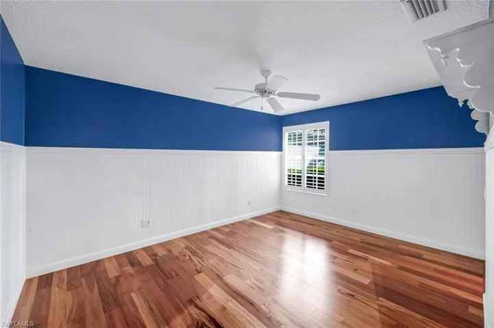 Spare room with a wainscoted wall, wood finished floors, a textured ceiling, and ceiling fan
