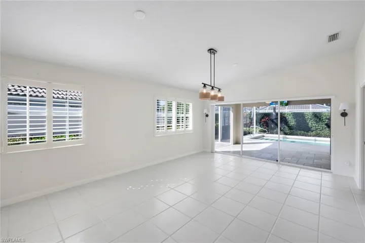 Unfurnished room featuring plenty of natural light, lofted ceiling, and light tile patterned flooring