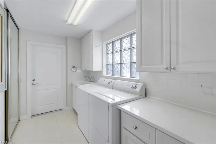Laundry area with light tile patterned flooring, cabinet space, and independent washer and dryer