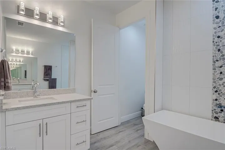 Bathroom featuring a freestanding tub, vanity, and light wood-type flooring