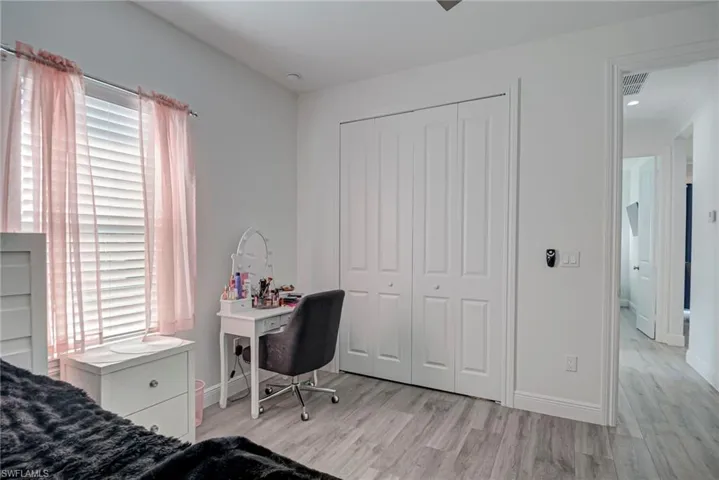 Bedroom with light wood-style floors, a closet, and an office area