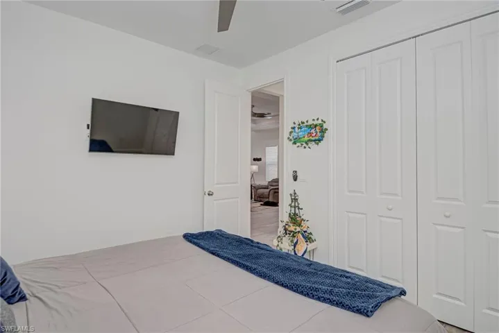 Tiled bedroom with a ceiling fan and a closet
