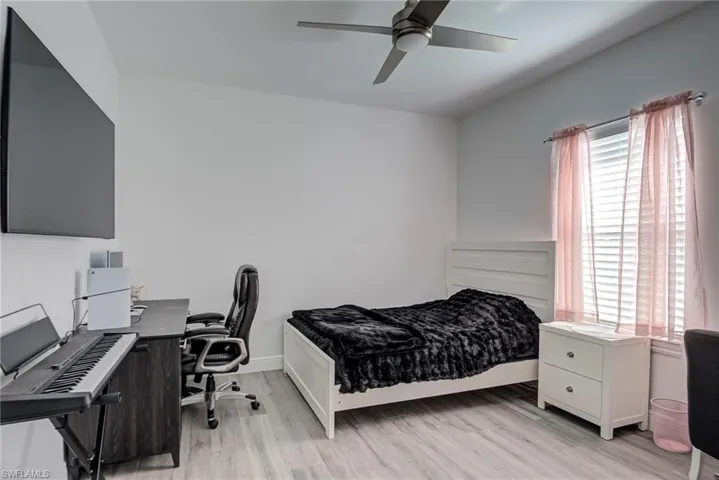 Bedroom with an office area, light wood-style floors, and ceiling fan