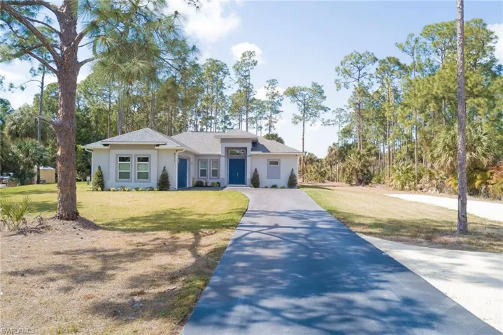 View of front facade featuring concrete driveway, a front yard, and stucco siding