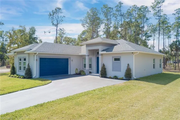Prairie-style home with roof with shingles, stucco siding, a front lawn, and a garage