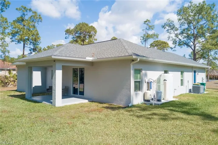 Back of house with a yard, stucco siding, roof with shingles, and a patio