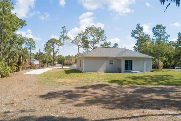 Rear view of house with stucco siding and a yard