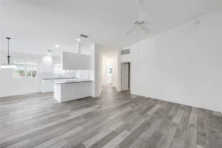 Kitchen with white cabinets, open floor plan, ceiling fan, light wood-type flooring, and a peninsula