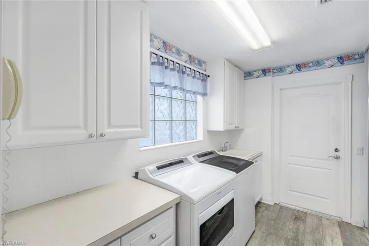 Laundry area with cabinet space, a textured ceiling, light wood-style flooring, and washer and clothes dryer