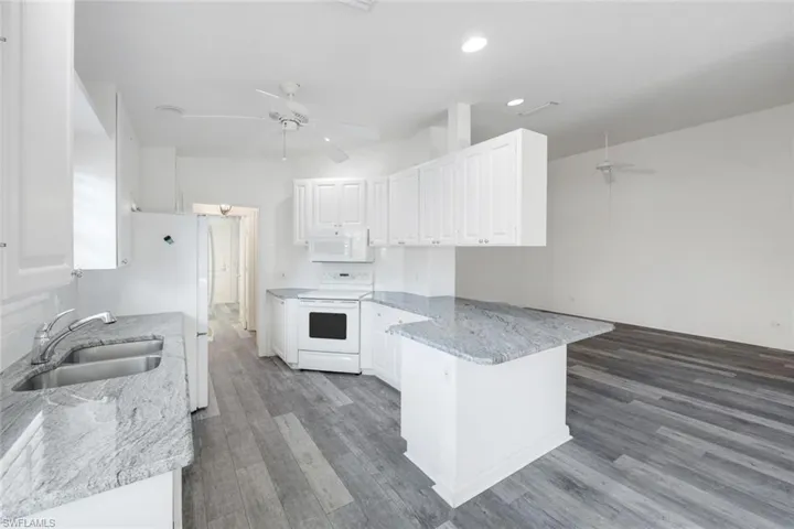 Kitchen with a ceiling fan, white cabinetry, white appliances, and light stone countertops