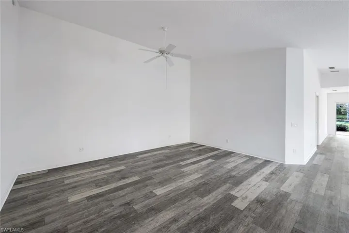Empty room with dark wood-style flooring and a ceiling fan