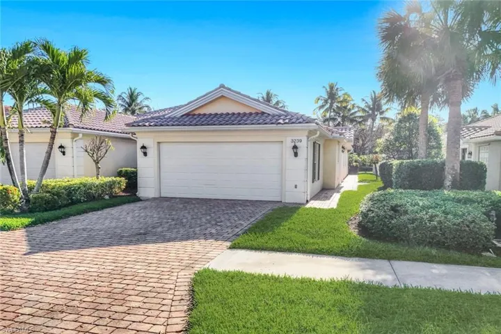 View of side of home featuring decorative driveway, a garage, stucco siding, and a tiled roof