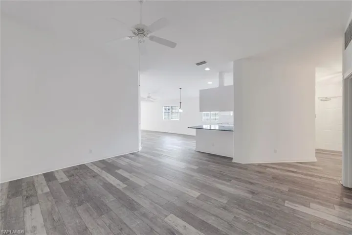 Unfurnished living room with ceiling fan, light wood-style floors, and lofted ceiling