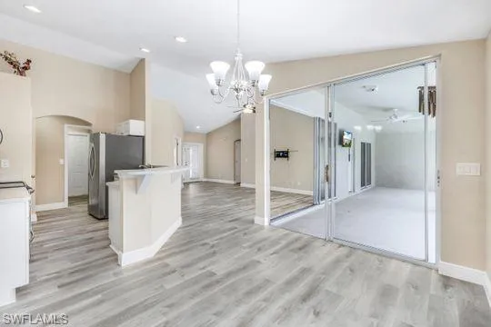 Kitchen featuring hanging light fixtures, stainless steel refrigerator, ceiling fan with notable chandelier, and white cabinets