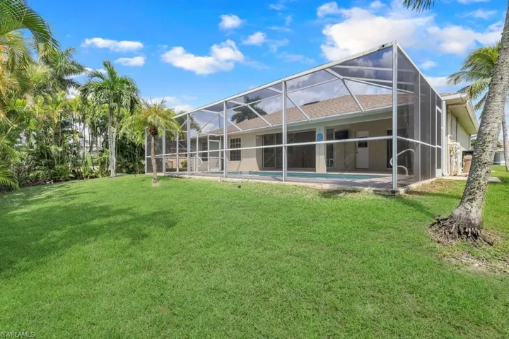 Back of property with glass enclosure, a yard, and a patio