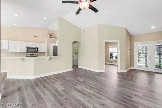 Unfurnished living room featuring high vaulted ceiling, light hardwood / wood-style flooring, and ceiling fan