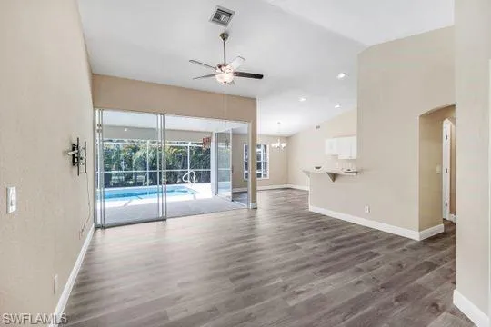 Unfurnished living room featuring vaulted ceiling, dark hardwood / wood-style flooring, and ceiling fan