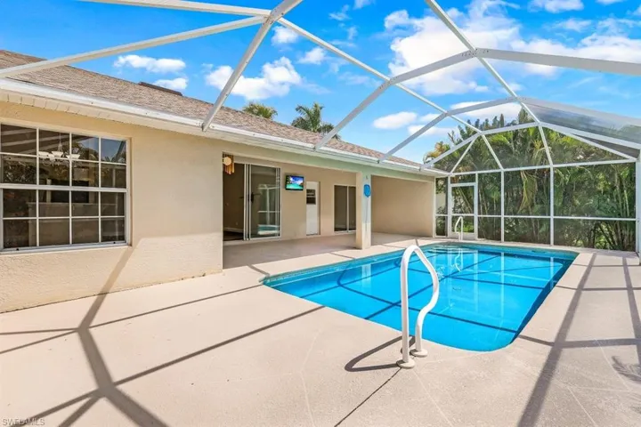 View of pool with a patio area and glass enclosure