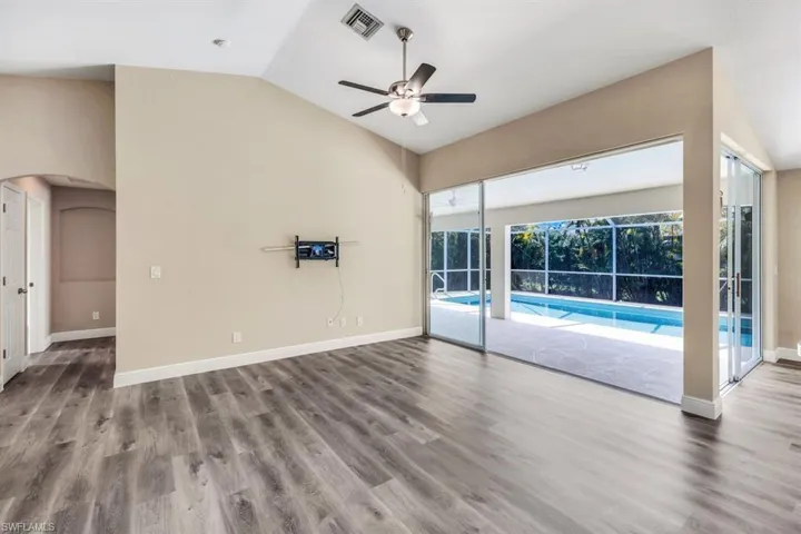 Unfurnished living room featuring wood-type flooring, ceiling fan, and vaulted ceiling