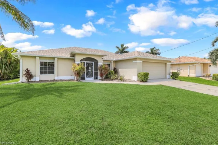 View of front facade featuring a garage and a front lawn