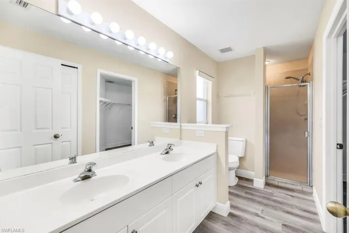 Bathroom featuring an enclosed shower, wood-type flooring, toilet, and vanity