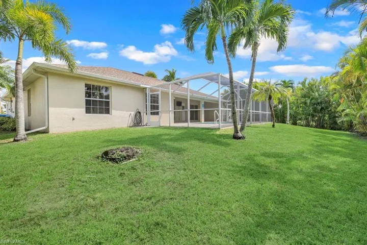 Back of house with glass enclosure and a yard