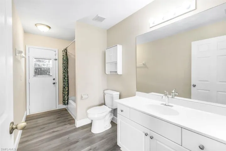 Full bathroom with vanity, toilet, hardwood / wood-style floors, and shower / bath combination with curtain
