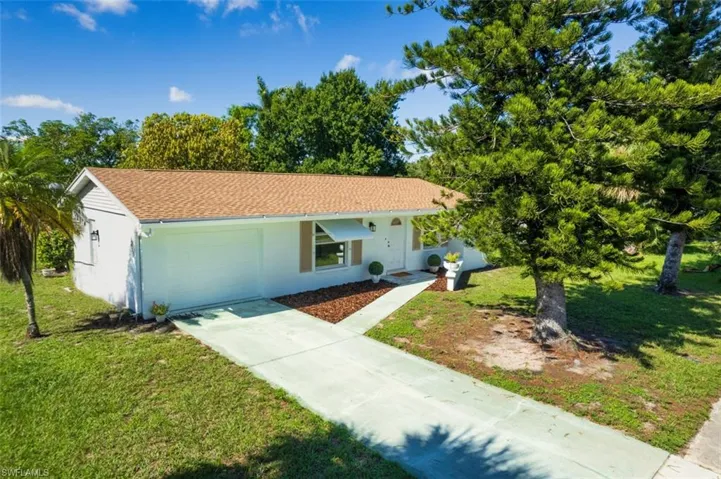 Ranch-style house with an attached garage, driveway, and a front yard