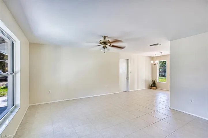 Empty room featuring a chandelier, a ceiling fan, and light tile patterned floors