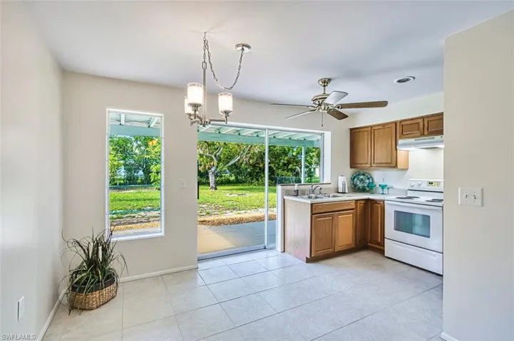 Kitchen featuring a chandelier, brown cabinetry, electric range, light countertops, and hanging light fixtures