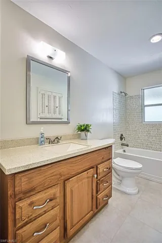 Bathroom featuring shower / tub combination, vanity, and light tile patterned flooring