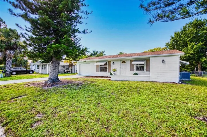 Ranch-style home featuring a garage, concrete driveway, and a front yard