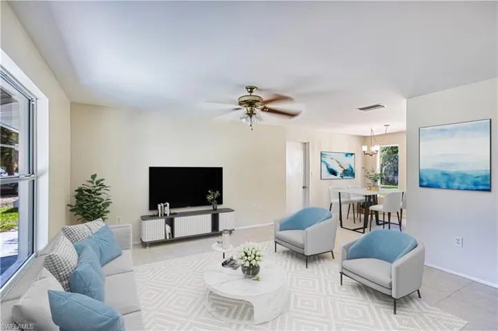 Living room featuring a chandelier, tile patterned flooring, ceiling fan, and healthy amount of natural light Virtual staged