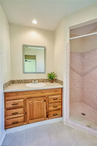 Full bathroom with a shower stall, vanity, light tile patterned floors, a textured wall, and recessed lighting