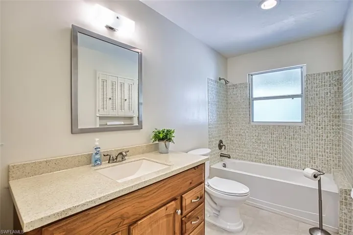 Bathroom featuring shower / bath combination, vanity, and light tile patterned floors